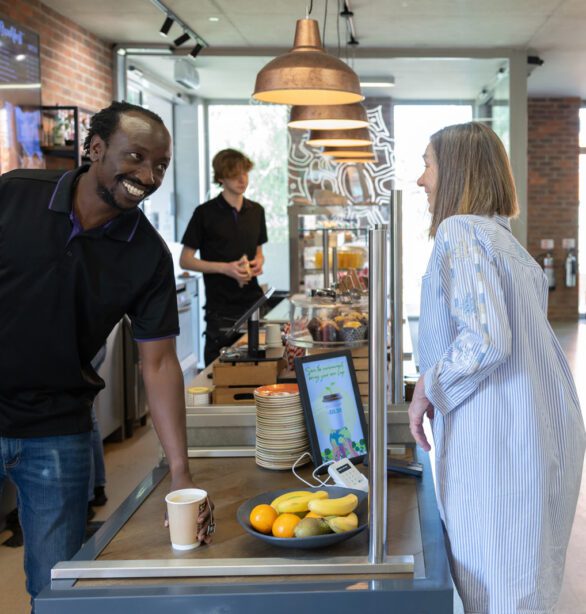 A man serves a woman a coffee from behind a cafe counter
